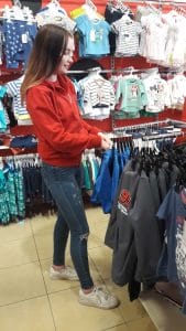 "Girl looking at children clothes at clothing store"