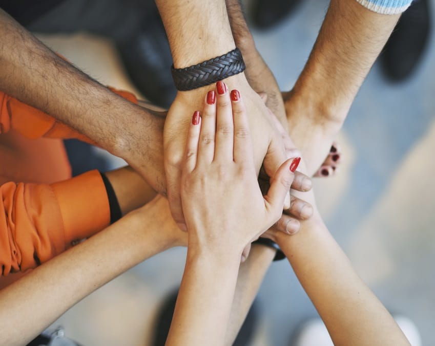 Multiethnic group of young people putting their hands on top of each other