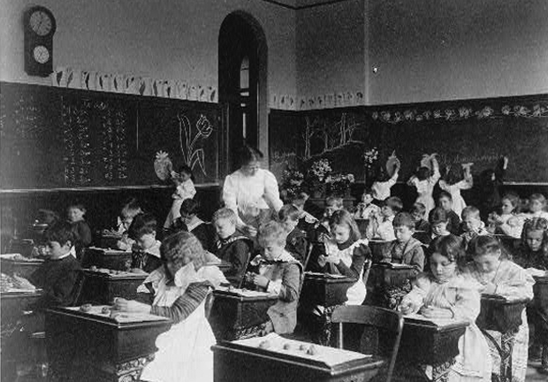 Old grayscale picture of classroom with teacher and students